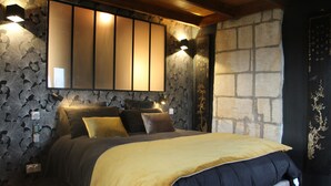 A bedroom with a bed, a large mirror, and stone walls.