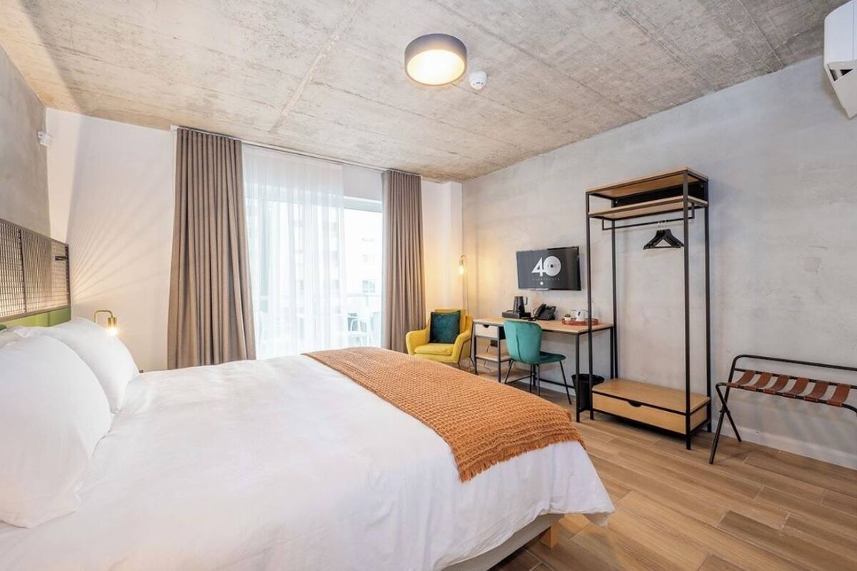 Ein modernes Hotelzimmer mit einem großen Bett, einem Schreibtisch, einem Stuhl und einem Kleiderhaken.
