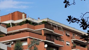 Un edificio de varios pisos con balcones, antenas parabólicas y un cielo azul despejado.