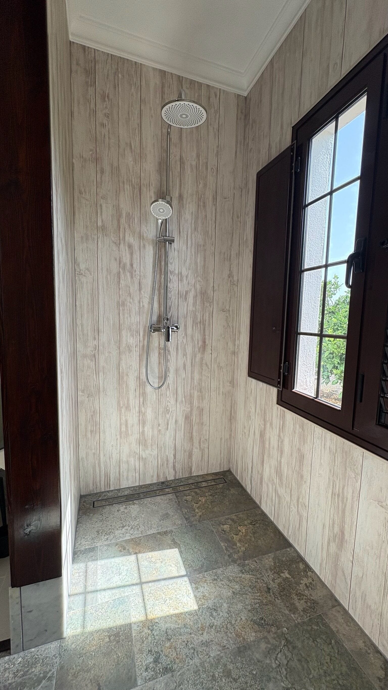 Un baño con ducha, ventana y puerta.