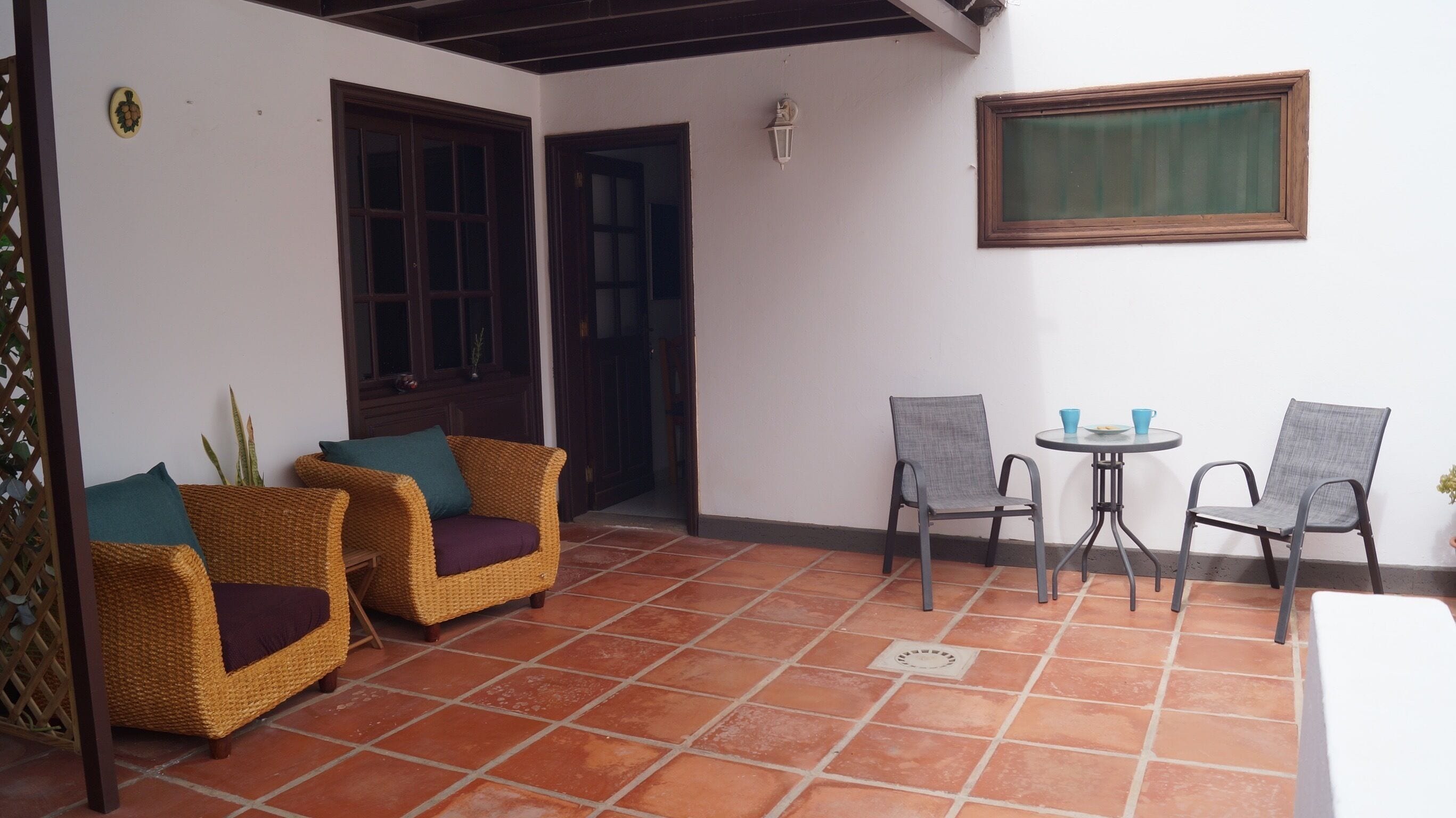 A patio with wicker chairs, a small round table, and a window.