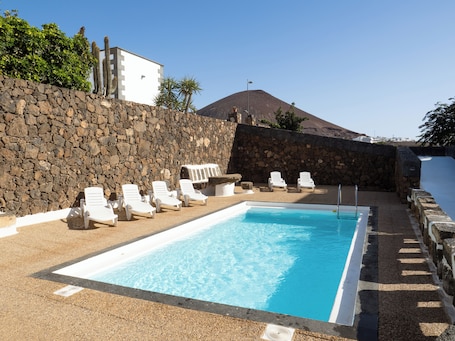 Una piscina al aire libre, sillones reclinables de piscina