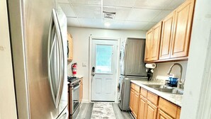 A kitchen with wooden cabinets, a stainless steel refrigerator, and a gray floor.