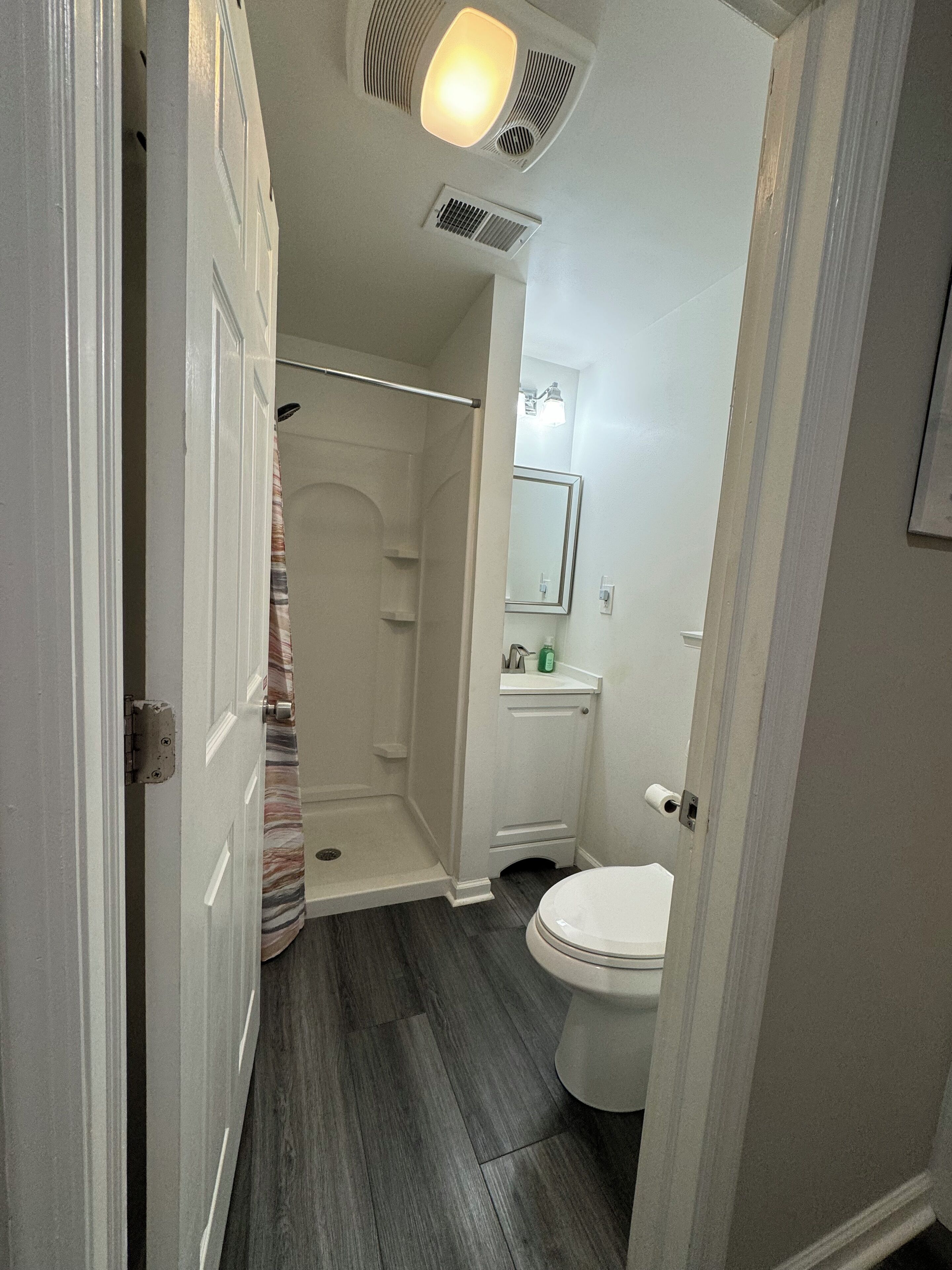 A bathroom with a shower, toilet, and vanity.