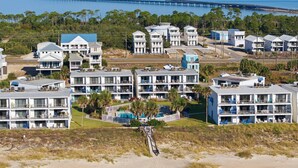 Un hôtel situé sur la côte, composé de plusieurs bâtiments, avec une plage au premier plan et une jetée qui s’avance dans l’eau à l’arrière-plan.