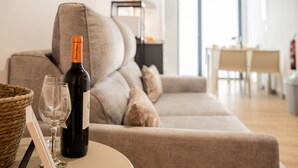 Un salon avec un canapé, une bouteille de vin et un verre posés sur une table.