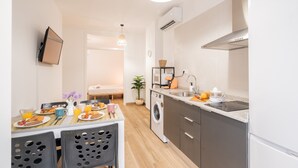 Een kleine keuken met een wasmachine, een spoelbak en een aanrecht met een waterkoker en stukjes sinaasappel.