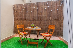 Relax in a serene outdoor space with a bamboo screen backdrop, a wooden table, and comfortable seating for two.