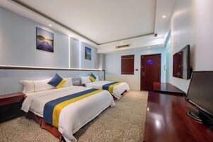 Ein Hotelzimmer mit zwei Betten, einem Flachbildfernseher und einem Schreibtisch.