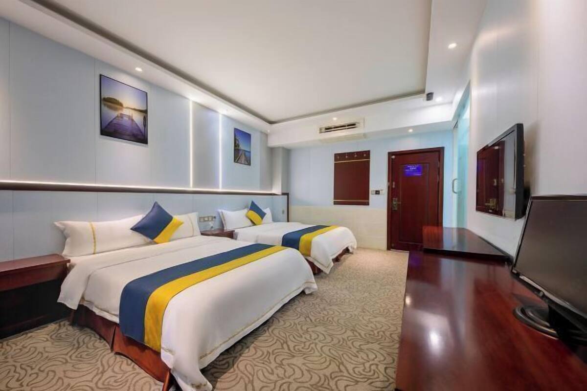 A hotel room with two beds, a flat-screen TV, and a large mirror.