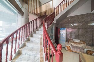 Eine imposante Treppe mit Marmorstufen und roten Balustraden, die zu einer oberen Etage führt.