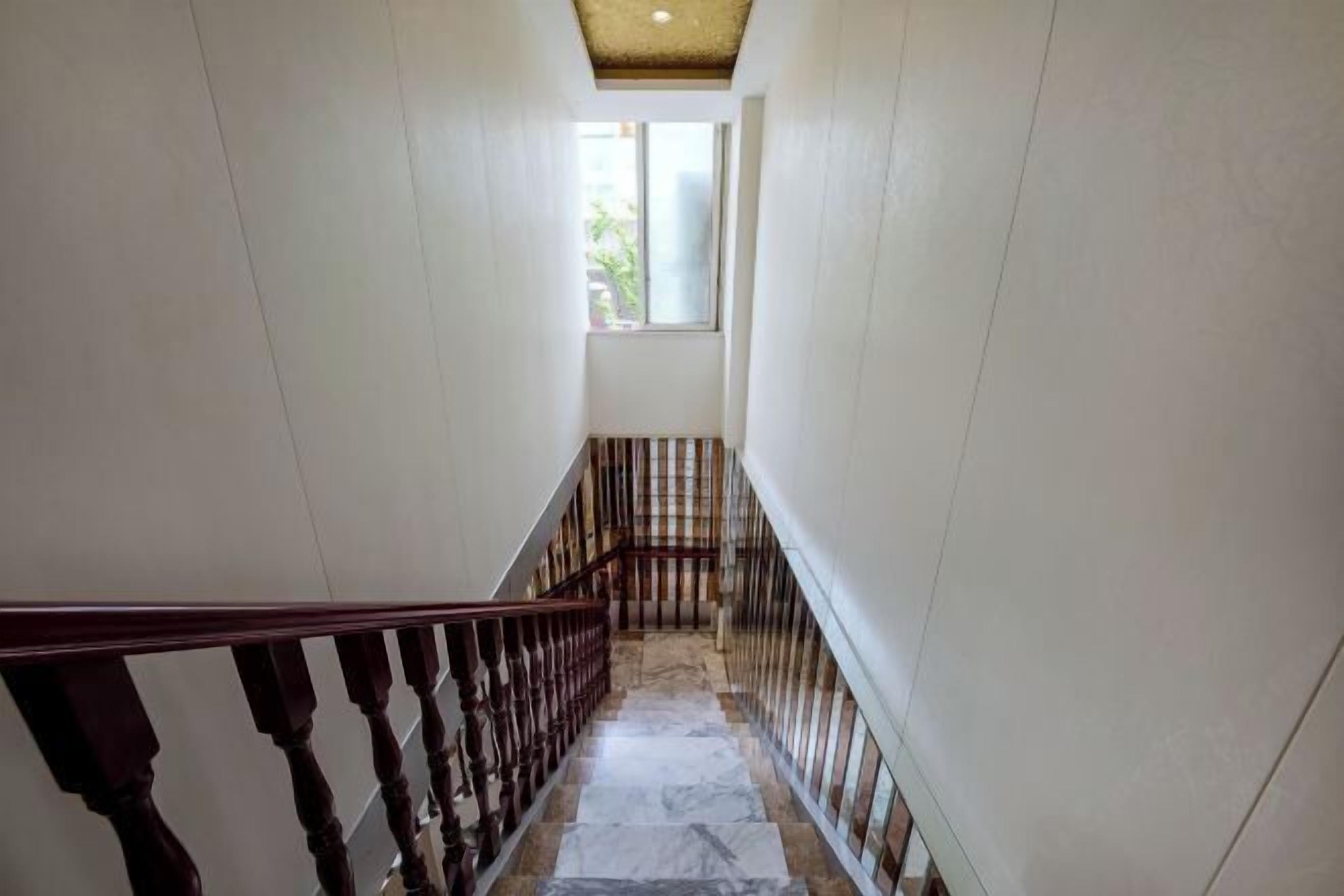 A narrow staircase with wooden railings and a tiled floor.