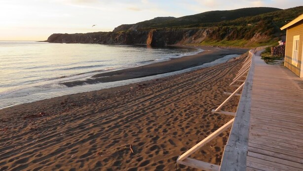 A beach with a wooden walkway leading to a building.