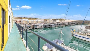 A marina with boats docked, a walkway alongside the water, and buildings in the background. - On the Water 5 A One-of-a-Kind Stay | Free Parking | By My Getaways (Brighton)