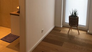 A modern interior with a wooden floor, a potted plant, and a door leading to a bathroom.