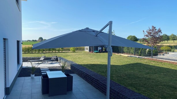 A patio area with a large umbrella, outdoor furniture, and a view of the surrounding landscape.