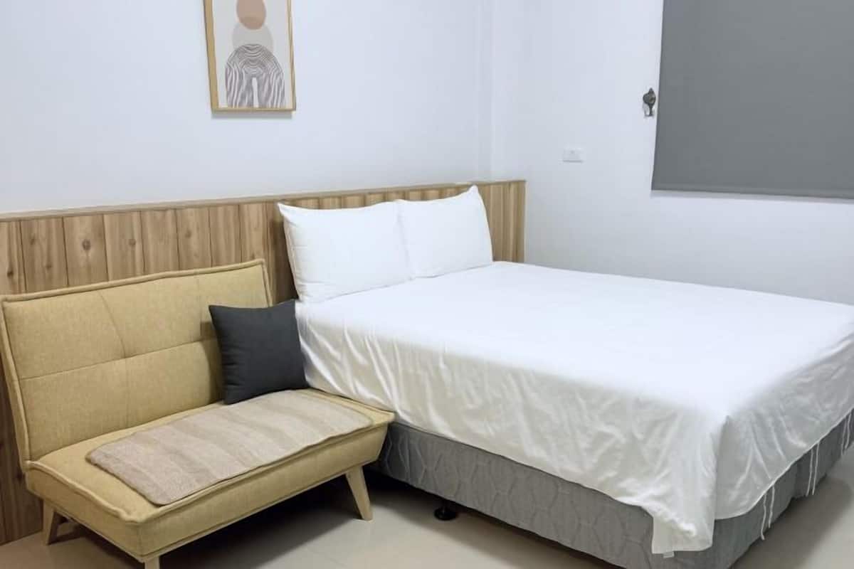 Un dormitorio con una cama, un sofá y una mesita.