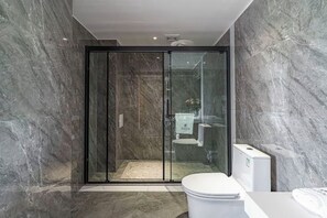 Une salle de bain moderne avec une douche à parois de verre, des murs en marbre et des toilettes blanches.