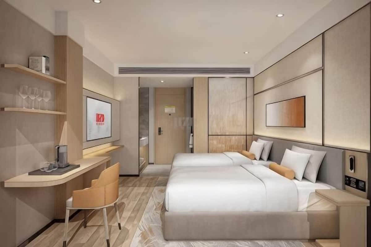 Een moderne hotelkamer met een bed, nachtkastje, bureau, stoel en kunst aan de muren.