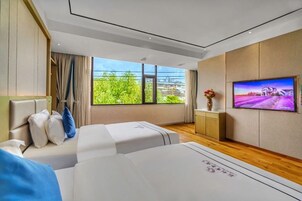 Una habitación de hotel moderna con un ventanal grande, un televisor de pantalla plana y un sofá.