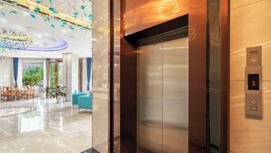 A modern elevator with a digital display showing the number 1, surrounded by polished marble flooring and a decorative ceiling. - Ningyu Lianchuang Business Hotel (Ning'er)