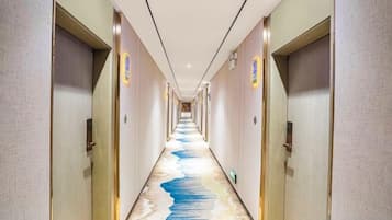 A hotel corridor with doors on both sides, a patterned floor, and a long hallway.