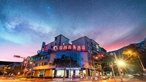 A hotel with a prominent sign, a multi-story structure, and a visible intersection with traffic lights. - Ningyu Lianchuang Business Hotel (Ning'er)