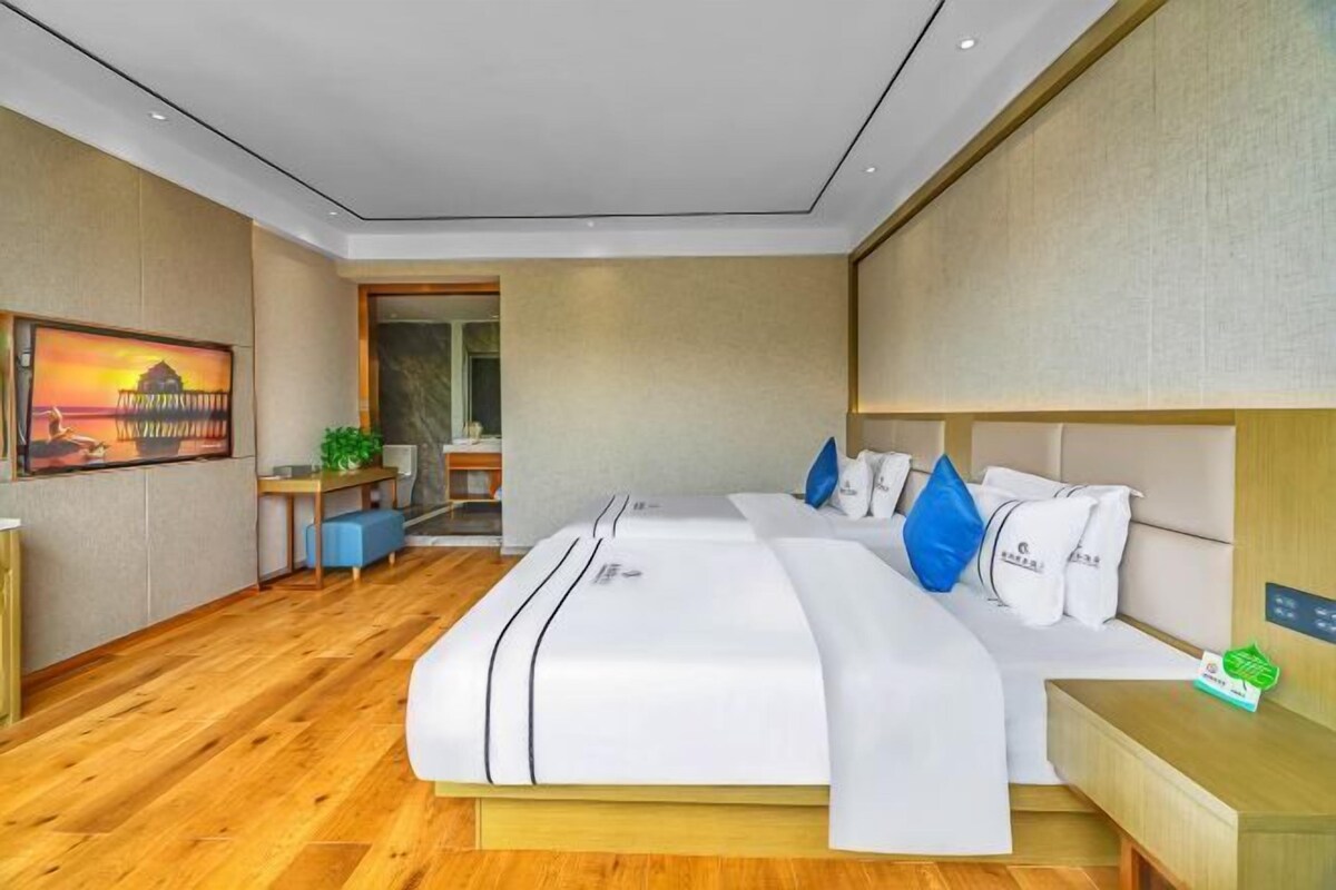 Ein modernes Hotelzimmer mit einem großen Bett, Nachttischen, einem Schreibtisch und Blick ins Freie.