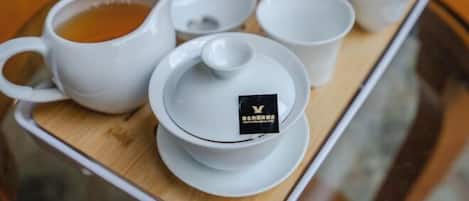A tray with a teapot, cups, and a teapot lid, all in white.