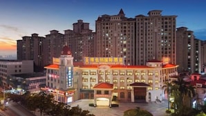 A hotel with a central courtyard, multiple floors, and a prominent tower with a red roof. - Vienna International Hotel (Guangzhou Xintang High Speed Railway Station Cowboy City Branch) (Guangzhou)