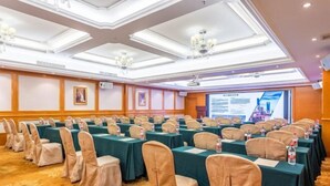 A conference room with rows of tables and chairs, a projector screen, and a ceiling with chandeliers. - Vienna International Hotel (Guangzhou Xintang High Speed Railway Station Cowboy City Branch) (Guangzhou)