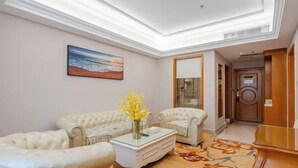 A spacious living room with a high ceiling, a large painting, and a floral rug. - Vienna International Hotel (Guangzhou Xintang High Speed Railway Station Cowboy City Branch) (Guangzhou)