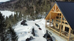 A lodge with a wooden exterior and a balcony, surrounded by snow-covered terrain and trees. - Auberge Boréale de Charlevoix (Petit-Saguenay)
