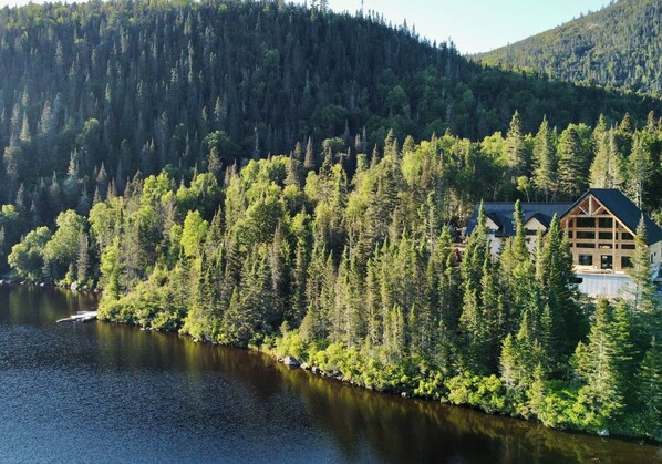 Una cabaña rodeada de un bosque denso y un lago.