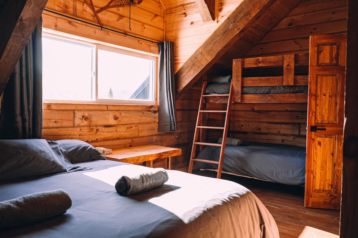 Een knus kamer met een slaapzolder, een ladder en een stapelbed.