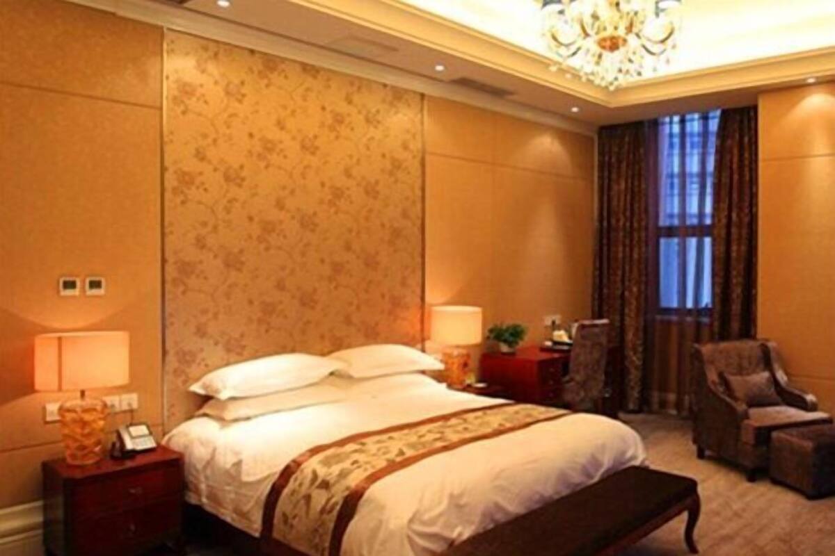 A hotel room with a large bed, a nightstand, a chair, and a window with curtains.