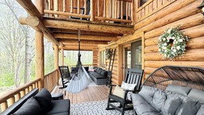 Et interiør af en hytte med balkon, siddepladser og en hængestol.