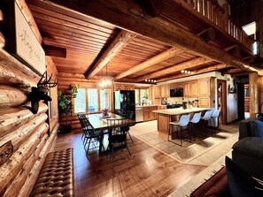 A log cabin interior with a dining area, kitchen, and bar seating.