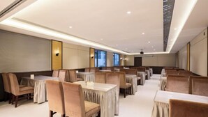 A hotel dining area with multiple tables and chairs, recessed ceiling lighting, and large windows. - Floral Hotel·Yangshuo Shiyin Yue Hotel (Yangshuo Xijie Shili Hualang Branch) (Yangshuo)