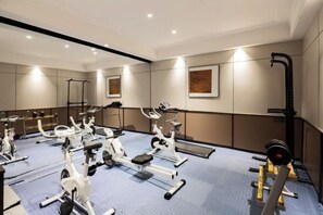 A gym with various exercise machines, a weight rack, and a mirror on the wall. - Floral Hotel·Yangshuo Shiyin Yue Hotel (Yangshuo Xijie Shili Hualang Branch) (Yangshuo)