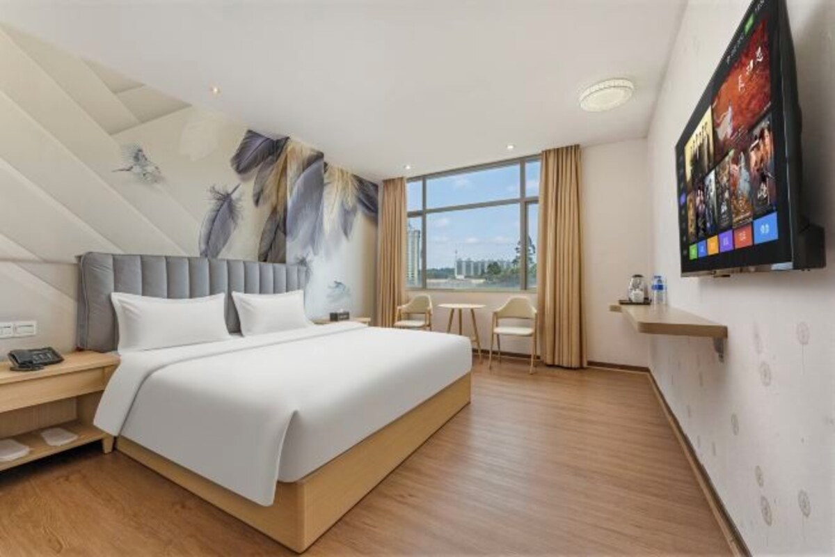 Une chambre d’hôtel moderne dotée d’un grand lit, d’un bureau, d’une chaise, d’une télévision et offrant une vue sur la ville.