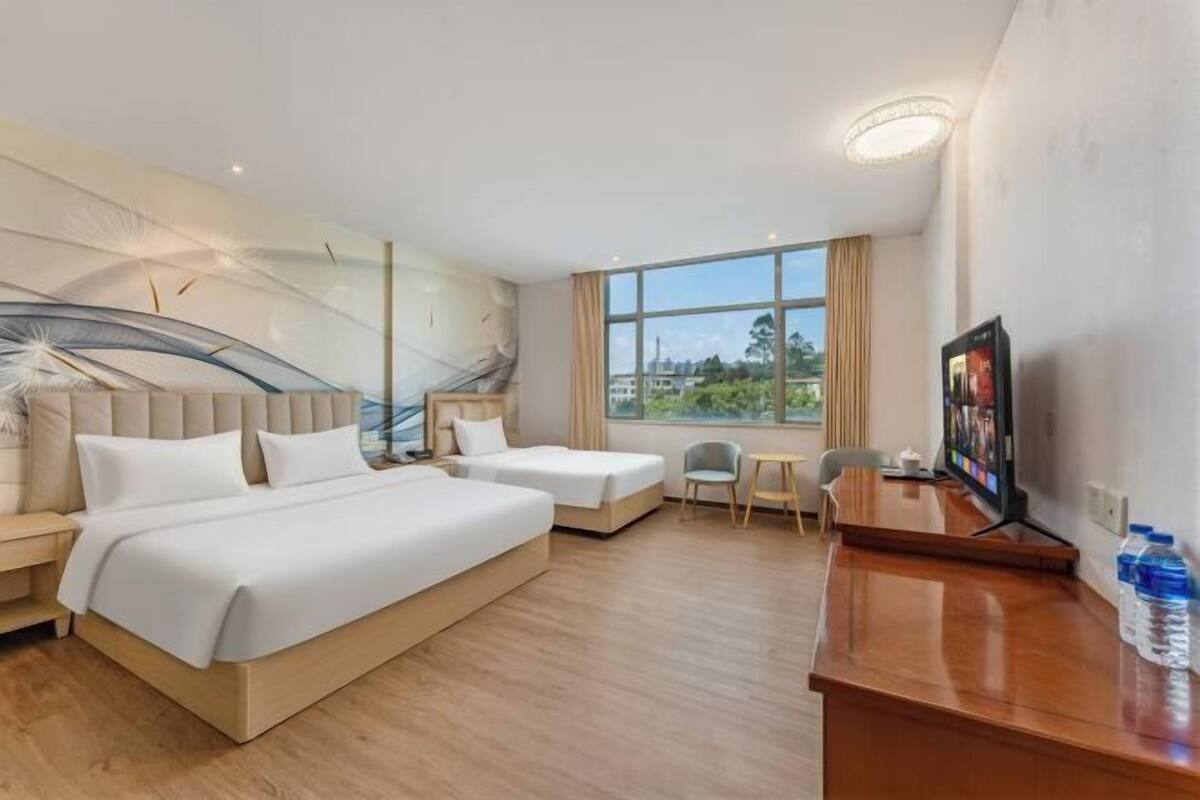 A hotel room with a large bed, a smaller bed, a desk with a computer, and a TV.