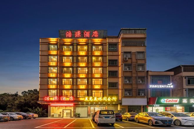 A multi-story hotel with a prominent entrance, several parking spaces, and a visible storefront with signage.
