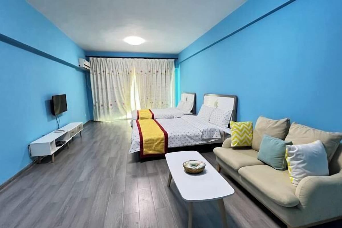 A room with a bed, a sofa, a TV, and a small table.