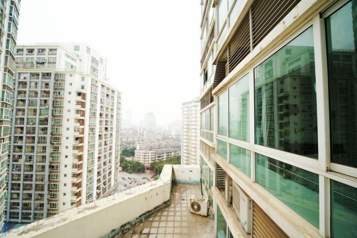 Un immeuble de grande hauteur doté de nombreux balcons, de grandes fenêtres et offrant une vue sur d’autres bâtiments.