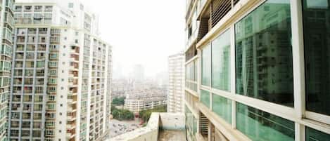 A high-rise building with multiple balconies, large windows, and a view of other buildings.