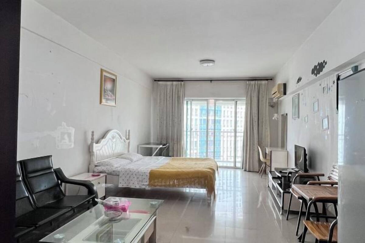 A hotel room with a bed, a desk, a chair, a TV, and a window with curtains.