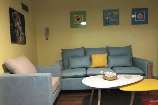 En stue med sofa, rundt sofabord og et gult tilhørsbord.