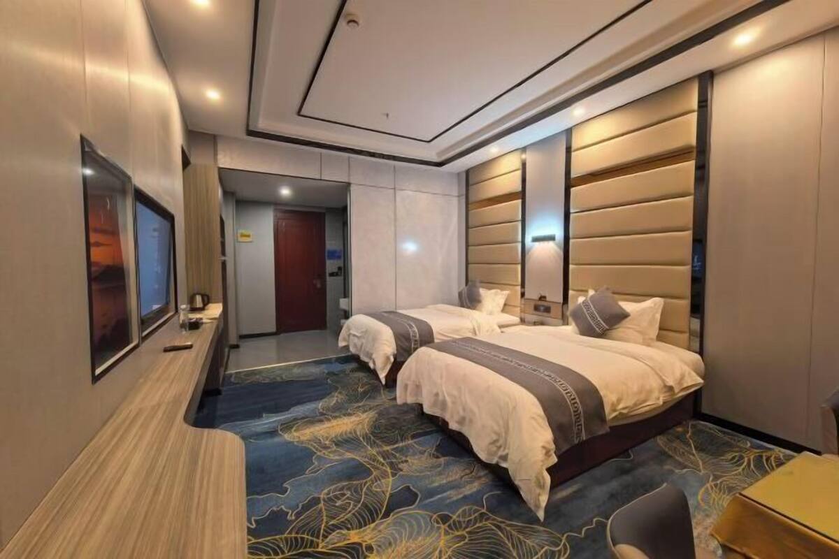 Quarto de hotel com duas camas, uma escrivaninha e uma cadeira.