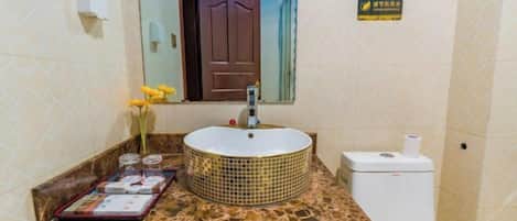 A bathroom with a round sink, a toilet, and a mirror.